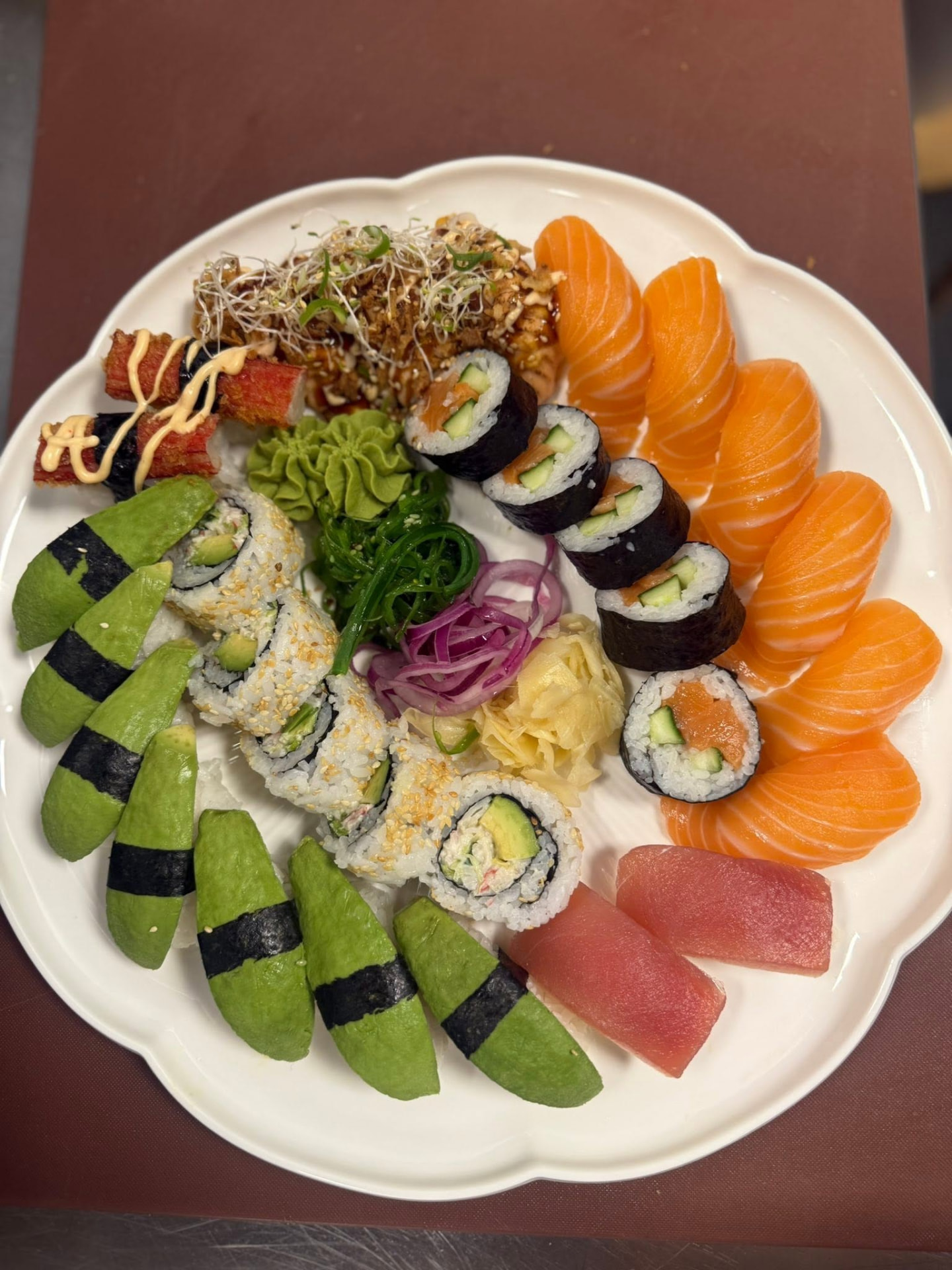 Stor sushibricka med nigiri, maki och avokadosushi på vitt fat